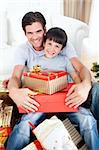 Happy father and son holding Christmas gifts in the living-room