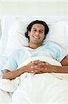 Portrait of a smiling patient lying in a hospital bed. Medical concept.