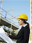 female engineer holding blueprints in construction site