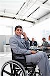 Smiling businessman on phone sitting in a wheelchair at a meeting