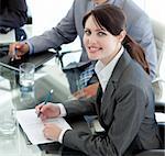 Smiling businesswoman studying a document in a meeting with her colleagues