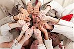 Successful business team with thumbs up lying on the floor in a circle