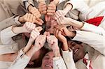 Smiling business people with thumbs up lying on the floor in a circle