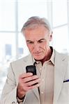 Concentrated senior businessman sending a text in the office