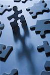 Backlit jigsaw puzzle pieces with one standing up and looking anthropomorphic