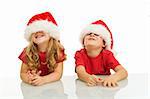 Two kids having fun with santa hats at christmas time - isolated