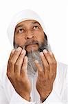 Stock image of Arab man praying over white background, selective focus on hands