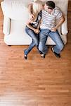 Young couple sitting on a cream colored love seat and kissing. Vertical shot