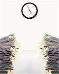 Stock image of two stacks of paperwork on desk, clock says it's almost time to leave...