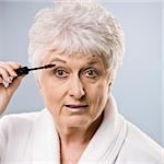 Older woman putting on makeup. Square framed shot.