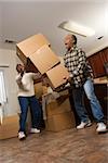 Senior african american man dropping stacked moving boxes while his wife attempts to catch them.