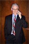 Businessman smiling while talking on his mobile phone. Vertical shot.