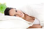 Portrait of beautiful smiling woman on bed at bedroom in white background