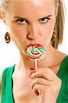 Glamorous young woman licking lollypop over white background