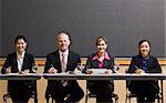 Business people smiling, sitting at table.  Horizontally framed shot.