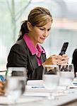 Businesswoman smiling with cell phone texting.  Vertically framed shot.