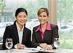 Businesswomen at meeting smiling.  Horizontally framed shot.