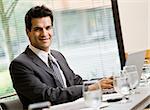 Man in business suit smiling working on laptop.  Horizontally framed shot.