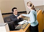 Businesswoman shaking hands with receptionist.  Horizontally framed shot.