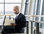 Young businessman with briefcase looking at folder.  Horizontally framed shot.
