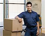 Young man standing next to stack of boxes.  Horizontally framed shot.