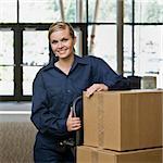 Young woman using hand truck to move boxes.  Vertically framed shot.