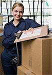 Young woman using hand truck to deliver boxes with delivery forms.  Vertically framed shot.