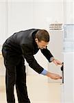 Business man getting water from water cooler. Vertically framed shot.