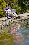 Woman using laptop near stream