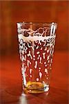 Empty beer glass on bar counter with residual foam lining the glass. Vertical shot.