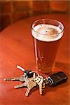 Car keys lying next to a full glass of beer.  Vertical shot.