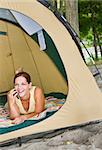 Woman laying in tent using cell phone