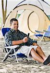 Man text messaging on cell phone at campsite