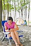 Woman text messaging on cell phone at campsite