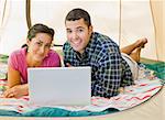 Couple laying in tent using laptop