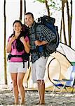 Couple carrying backpacks at campsite