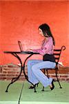 Young woman sitting at a table and using a laptop computer. Vertical shot.