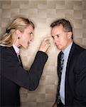 Caucasian mid-adult businesswoman yelling and pointing at middle-aged businessman. Vertical format.