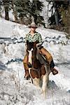 Attractive young woman riding a horse in the snow. Vertical shot.