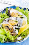 Oysters with lemon, spicery and salad on plate