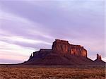 Mesa in Monument Valley with a rock formation in the background at dusk. Horizontal shot.