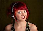 Pretty punky girl with brightly dyed red hair listening to music