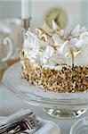 Cream cake with sliced nuts on glass cake stand