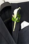 Suit jacket hanging on a hanger with a boutonniere in place.