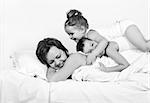 Mother and children on the bed having fun - high key - focus on woman face