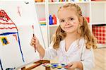 Happy little artist - girl painting a house on a large white sheet