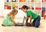 Kids playing on laptops - boy teaching little girl what key to press