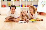 Happy family with a child laying on the floor preparing to read a story in the kids room