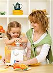 Woman and little girl making juice with fresh fruits in the kitchen