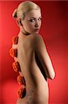 cute blond girl on red background with some red flowers on her back looking in camera